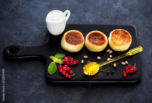 Pancakes Syrniki with cottage cheese, berris, sour cream and honey. Delicious and healthy breakfast photo