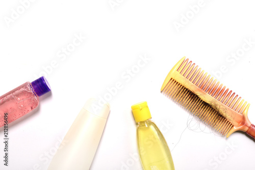 Comb with hair and shampoo on white background