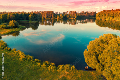 Aerial view of the beautiful calm lake surrounded by forest at sunset
