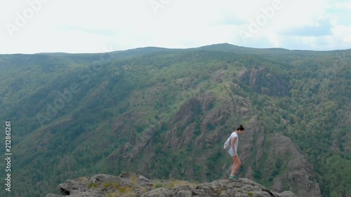 Drone Fly over impressive mountains with girl on a cliff face, vertigo effect photo