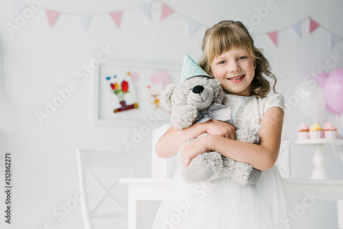 happy child holding and embracing teddy bear in cone