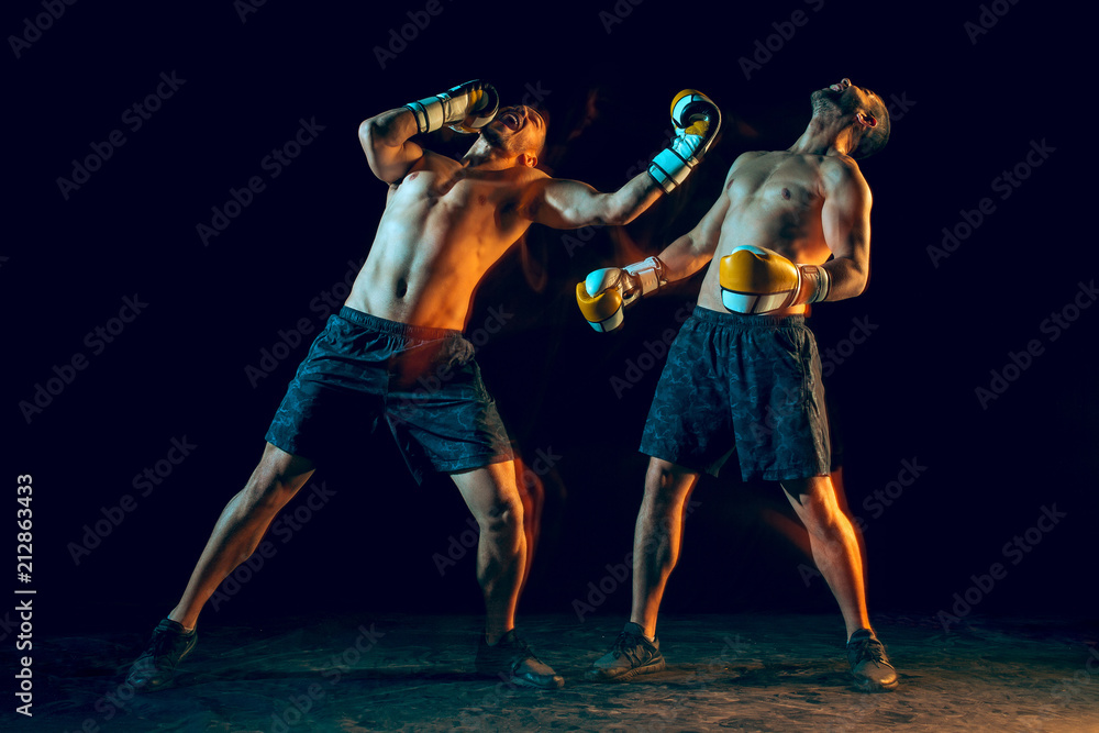 Male boxer boxing in a dark studio