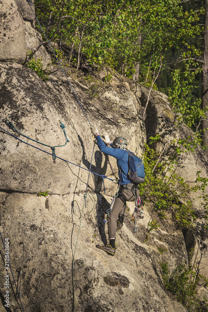 Obraz premium Climber in helmet and with special climbing equipment climbs on a rock