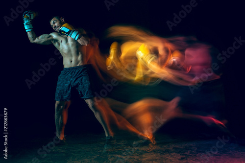 Male boxer boxing in a dark studio