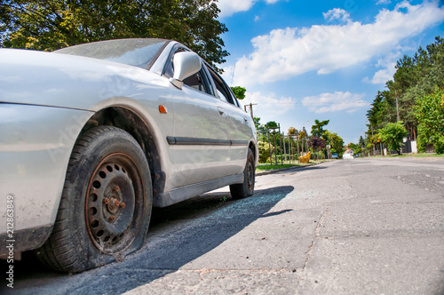 broken car in the background of the street and the blue sky. Broken side windows in the car. Street photography