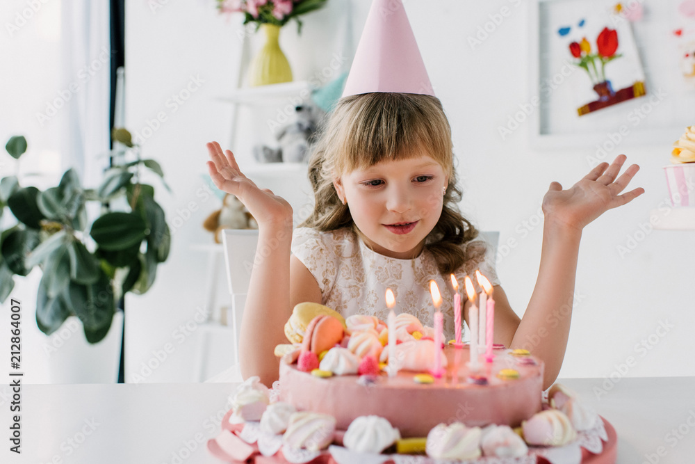 cute kid with wide arms looking at birthday cake with candles cute kid with wide arms looking at birthday cake with candles