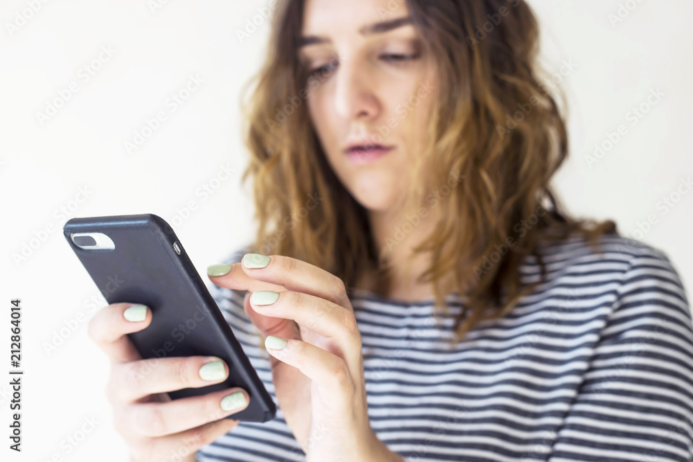 A girl is holding a smartphone and looking at the screen. Technology and online life A girl is holding a smartphone and looking at the screen. Technology and online life