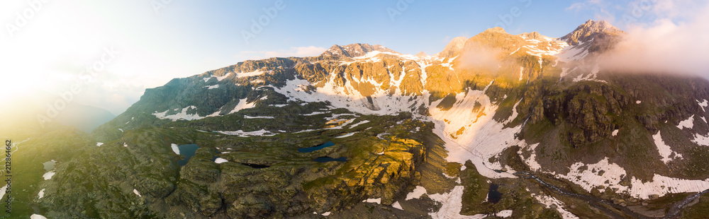 High altitude alpine landscape with majestic rocky mountain peaks. Aerial panorama at sunrise. Alps, Andes, Himalaya concept