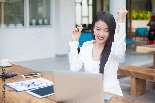 young Asia modern successful business woman holding a gold bitcoin Computer , and a tablet , bitcoin concept © Morakot