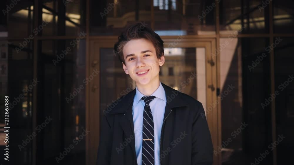 Portrait of petty Caucasian boy. wearing classic clothes on background of business center . Gorgeous young man with beautiful smile looking directly at camera. Outdoors. Portrait of petty Caucasian boy. wearing classic clothes on background of business center . Gorgeous young man with beautiful smile looking directly at camera. Outdoors.