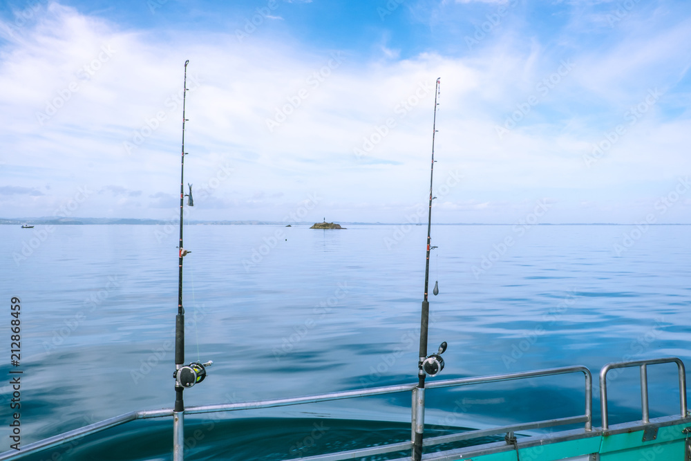 Fishing rods on a charter boat on calm, tranquil sea in Far North District, Northland, New Zealand, NZ Fishing rods on a charter boat on calm, tranquil sea in Far North District, Northland, New Zealand, NZ