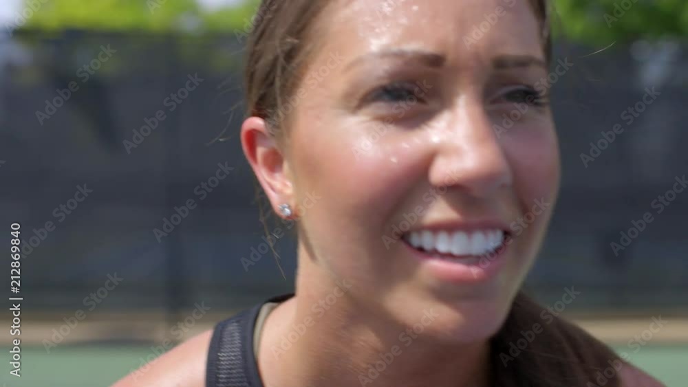 Closeup on a female tennis player getting ready to receive a serve, smiling and mouthing to her opponent to Closeup on a female tennis player getting ready to receive a serve, smiling and mouthing to her opponent to