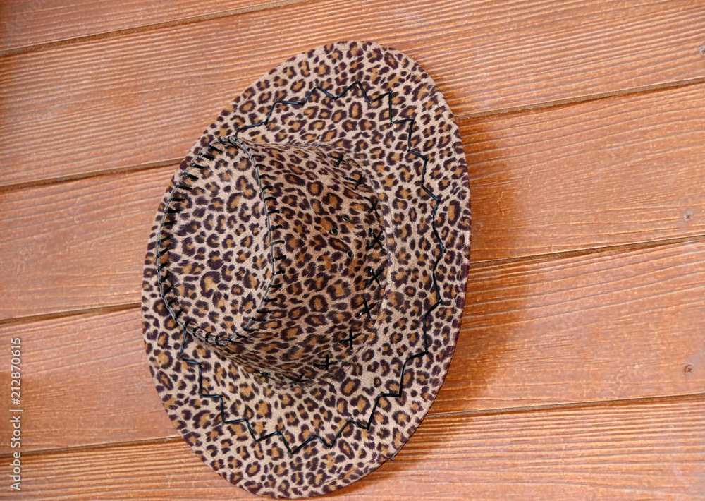 Leopard Tiger pattern fabric of hat hanging on the brown fiber cement wall for decoration.