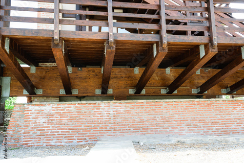 Suspended solid wood deck structure detail. Raised wooden deck and hand guard with brick wall foundation. © Florin
