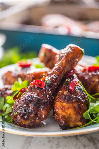 Grilled roasted and barbecue chicken legs on white plate.