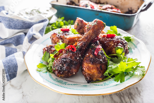 Grilled roasted and barbecue chicken legs on white plate.
