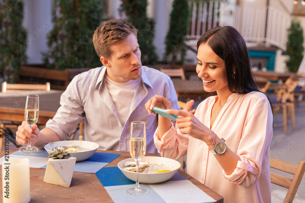 Furious man. Blonde-haired man feeling really furious sitting near blogger making photos of her food during date Furious man. Blonde-haired man feeling really furious sitting near blogger making photos of her food during date
