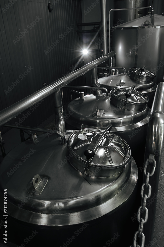 Craft beer brewery equipment. Modern beer plant with brewering kettles, tubesmade of stainless steel for alcoholic drink production. Industrial background