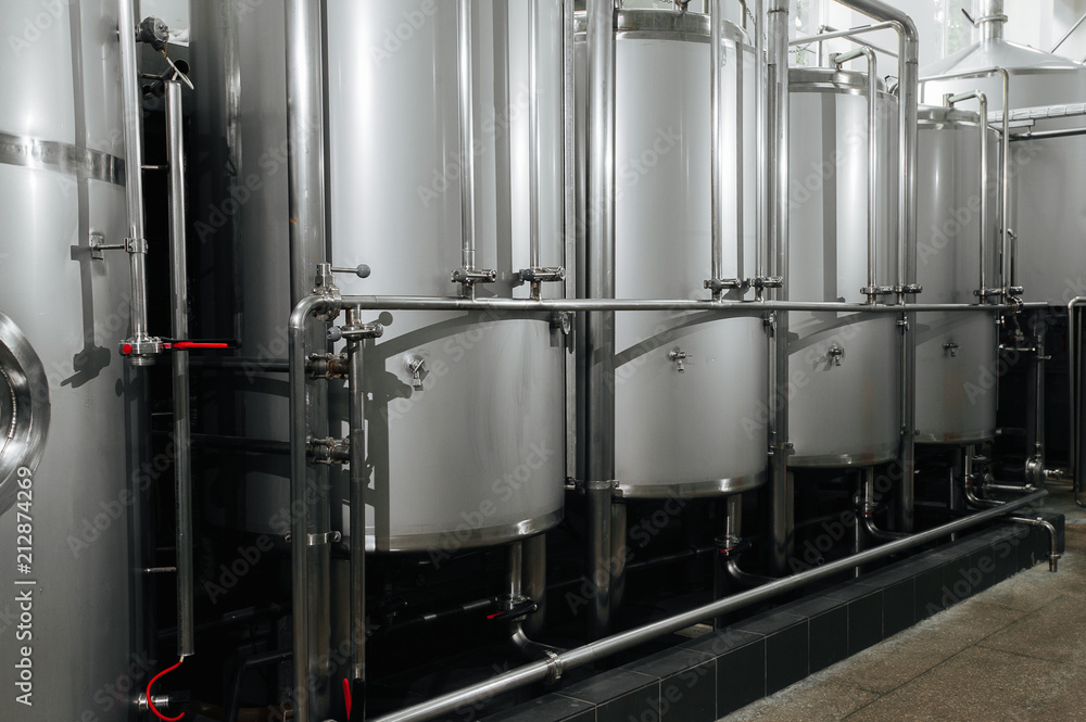 Craft beer brewery equipment. Modern beer plant with brewering kettles, tubesmade of stainless steel for alcoholic drink production.