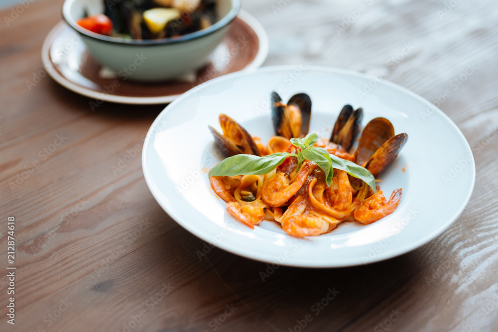 Pasta with seafood. Nice delicious dish with Italian pasta and tasty seafood in tomato sauce lying in white plate Pasta with seafood. Nice delicious dish with Italian pasta and tasty seafood in tomato sauce lying in white plate
