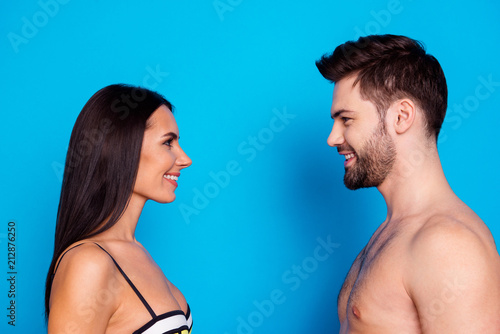 Half-faced side profile view portrait of happy woman and young man with beard who look at each other ans smile isolated on blue background with copy space for text