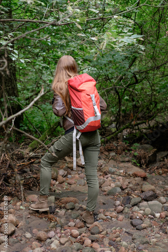 young redhead long hair woman travels in summer cloudy forest