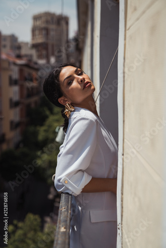 Portrait of young woman leaning on railing on balcony photo