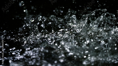 Water splash on black background color which represent clean and pure natural freshness of liquid for healthy drink or sparkling water © gnepphoto