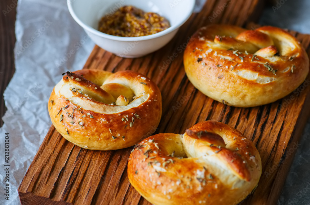 Traditional salted pretzels with oregano over wooden background. Oktoberfest or beer snack concept.