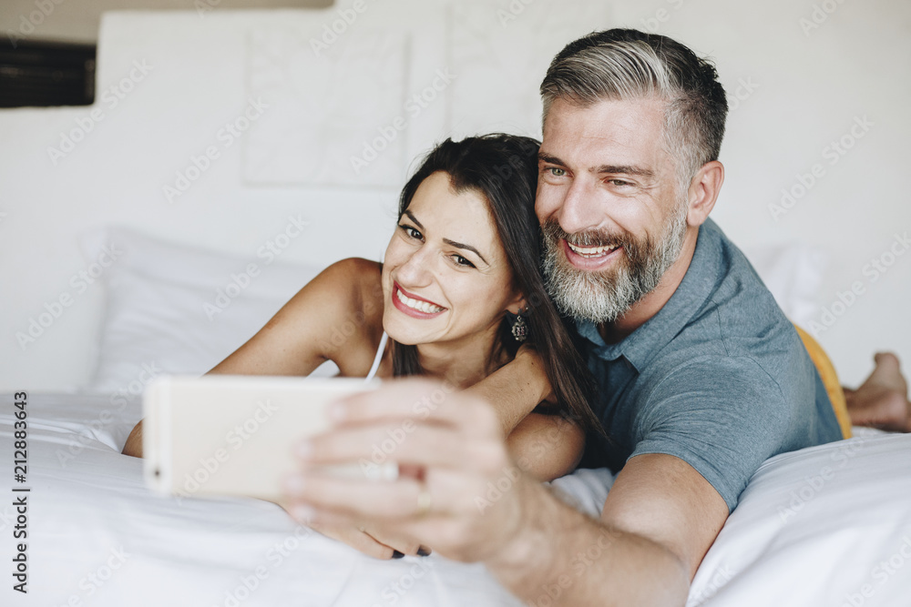 Fototapeta premium Honeymooners taking a selfie in bed