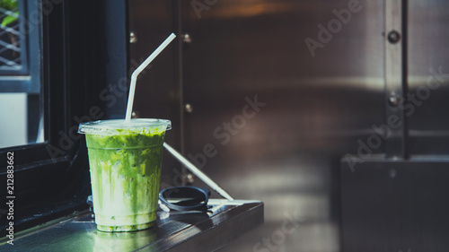 Green tea matcha atte in plastic cup with glasses by the windiw in cafe.