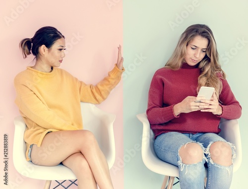 Women Friends are Sitting and Using Mobile Phones Indoor