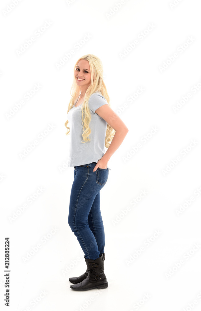 Fototapeta premium full length portrait of blonde girl wearing simple blue shirt and jeans, standing pose. isolated on white background.