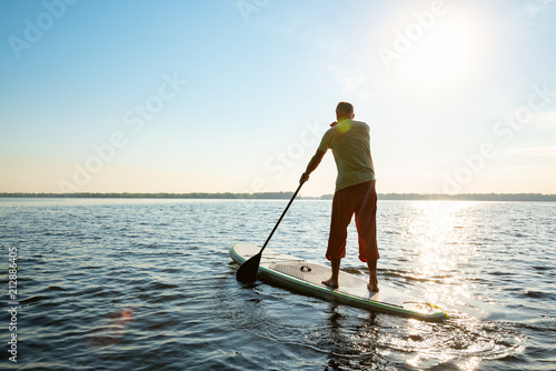 Man paddling on a SUP board along a large river