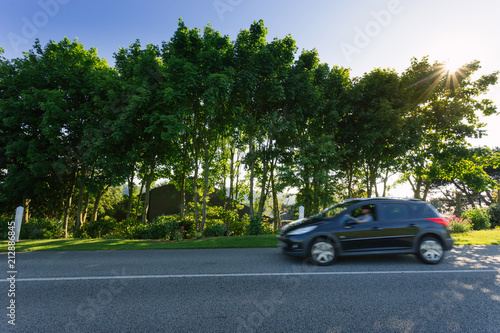 Empty asphalt country road passing through green forests and villages. Summer countryside landscape in the region of Normandy, France. Recreation, nature, holidays, travel and road network concept. © sergiymolchenko