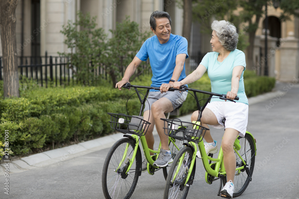 Cheerful senior Chinese couple riding bikes Cheerful senior Chinese couple riding bikes