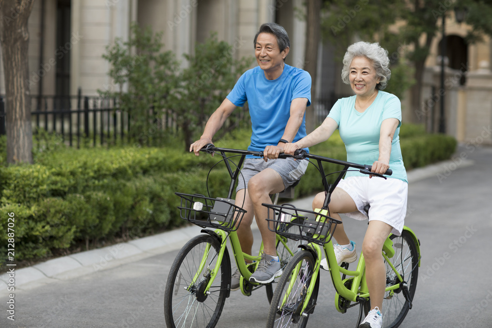 Cheerful senior Chinese couple riding bikes Cheerful senior Chinese couple riding bikes