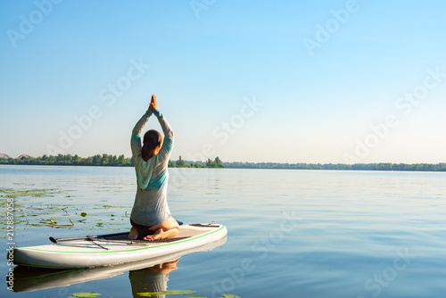 Female practicing yoga on a SUP board