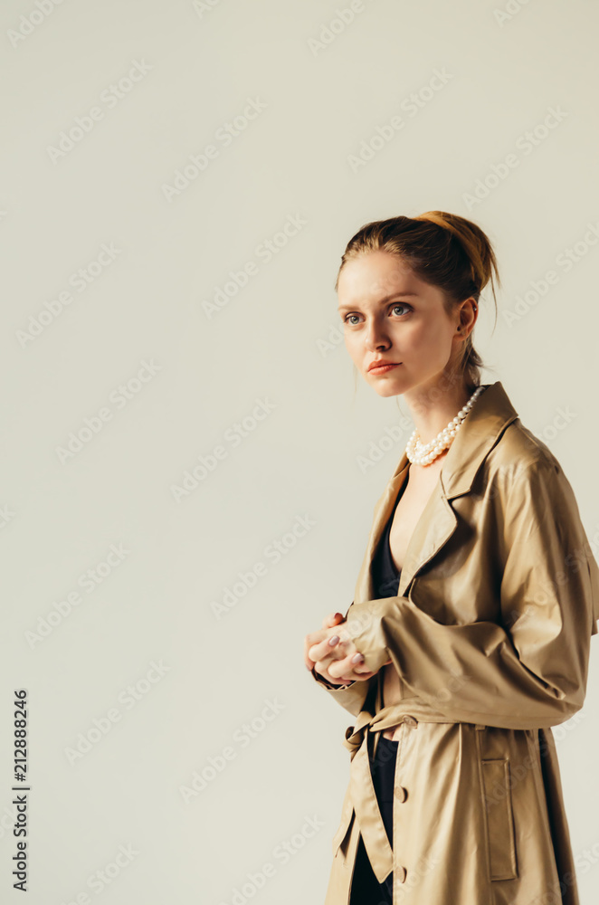 Studio portrait of young brunette girl wearing sexy cashmere coat standing on white wall background