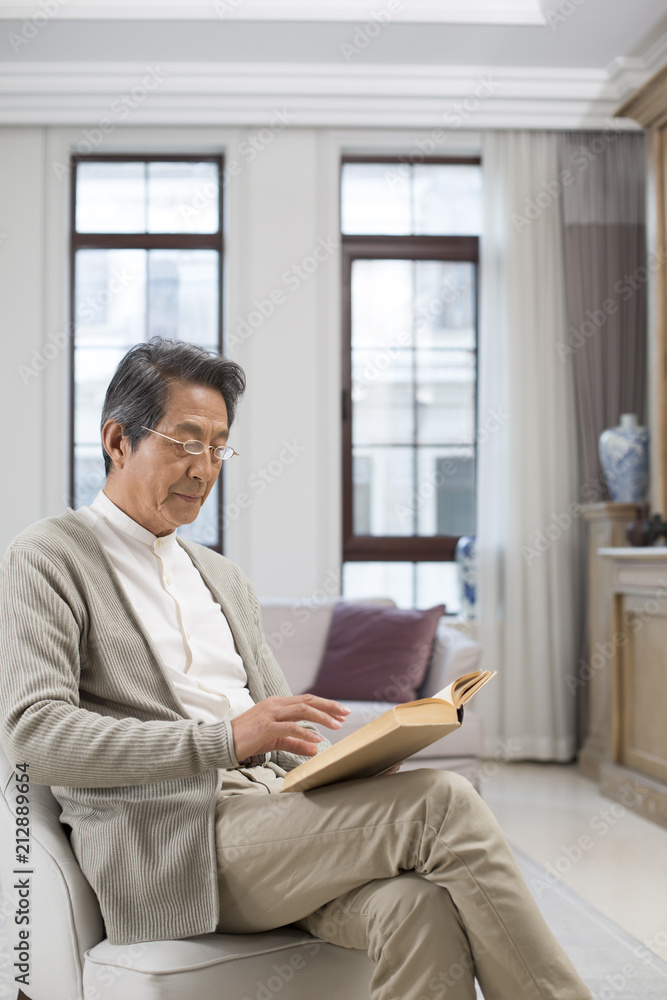 Senior Chinese man reading a book at home Senior Chinese man reading a book at home