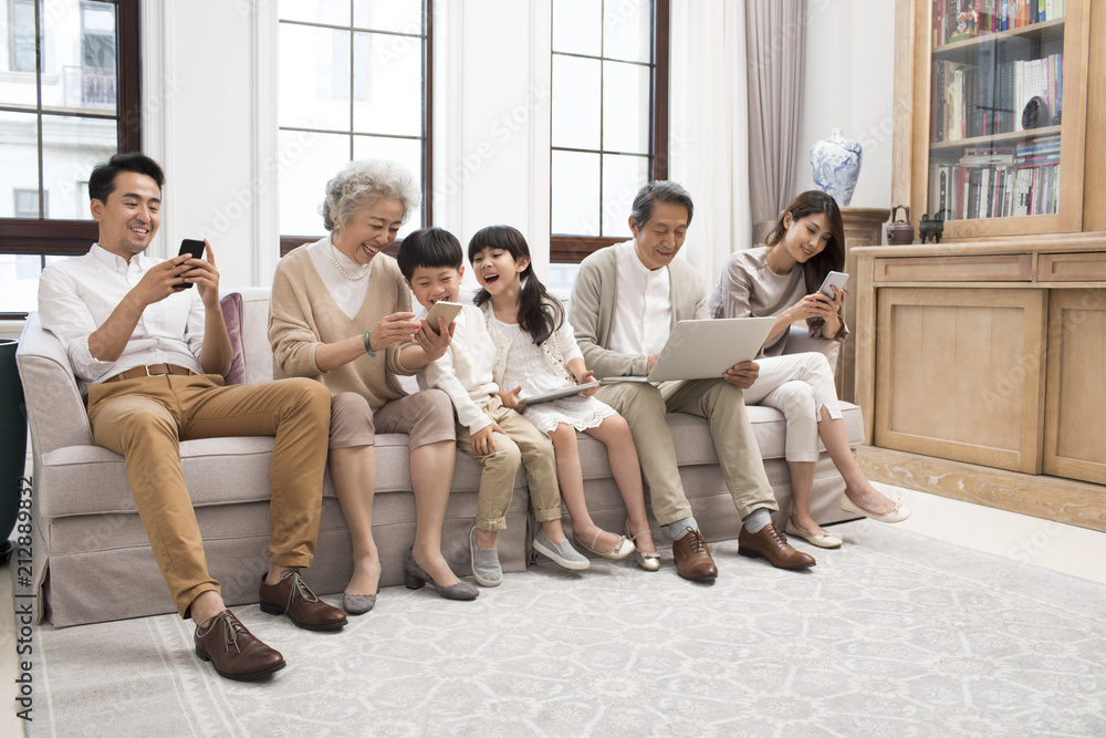 Happy Chinese family using digital devices on sofa Happy Chinese family using digital devices on sofa