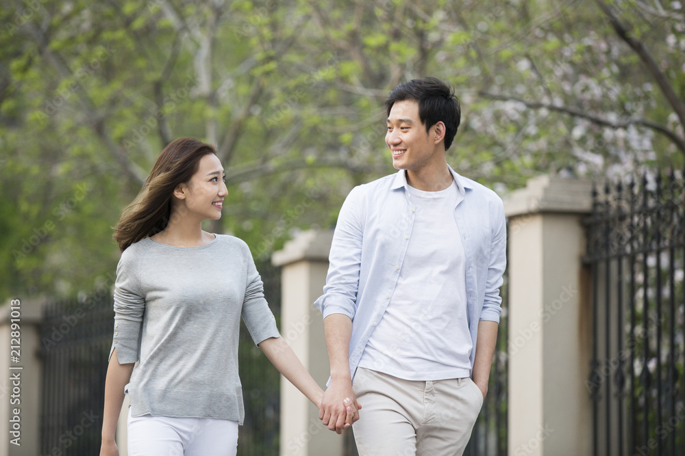 Happy young Chinese couple holding hands walking Happy young Chinese couple holding hands walking