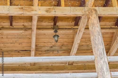 wooden ceiling of log house decorated garland and vintage lantern