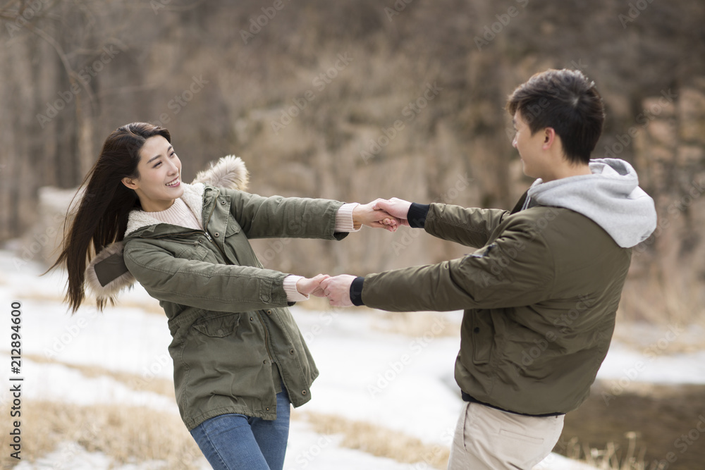 Happy young Chinese couple holding hands spinning Happy young Chinese couple holding hands spinning
