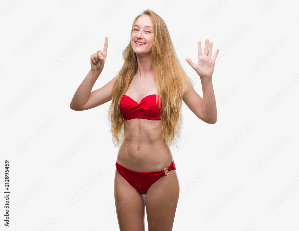 Blonde teenager woman wearing red bikini showing and pointing up with fingers number six while smiling confident and happy. Blonde teenager woman wearing red bikini showing and pointing up with fingers number six while smiling confident and happy.