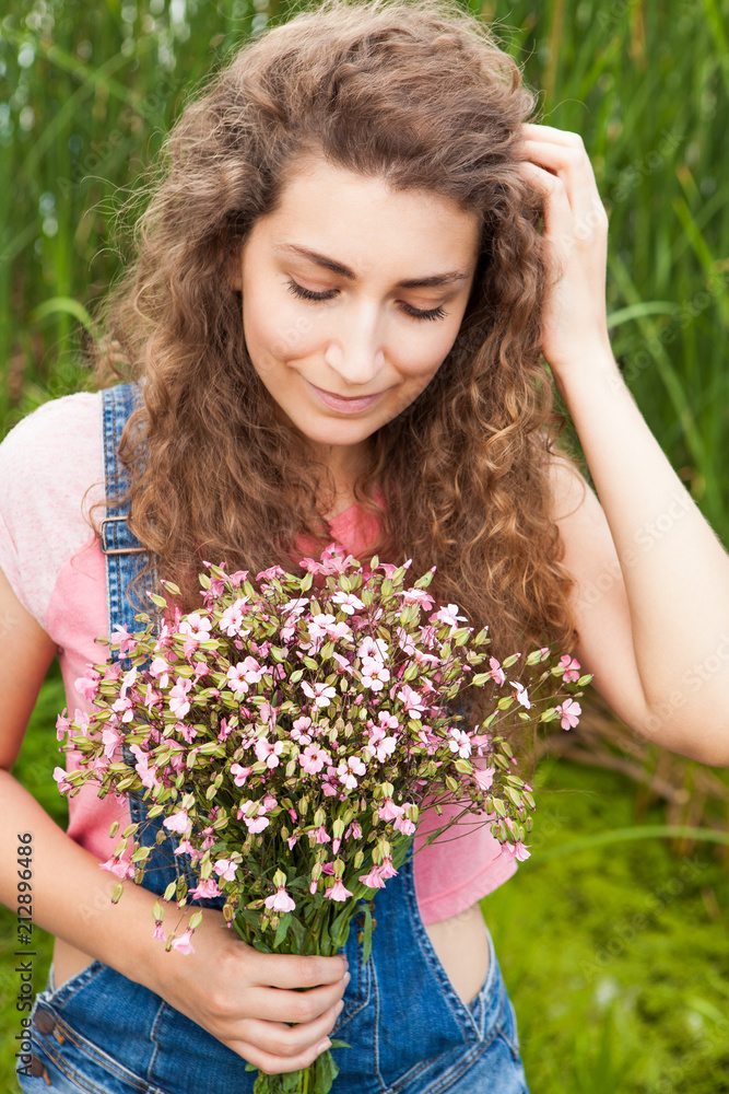 Beautiful woman with bouquet of pink flowers looking down, in summer Beautiful woman with bouquet of pink flowers looking down, in summer