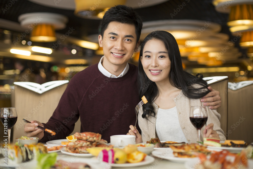 Cheerful young Chinese couple having buffet dinner Cheerful young Chinese couple having buffet dinner