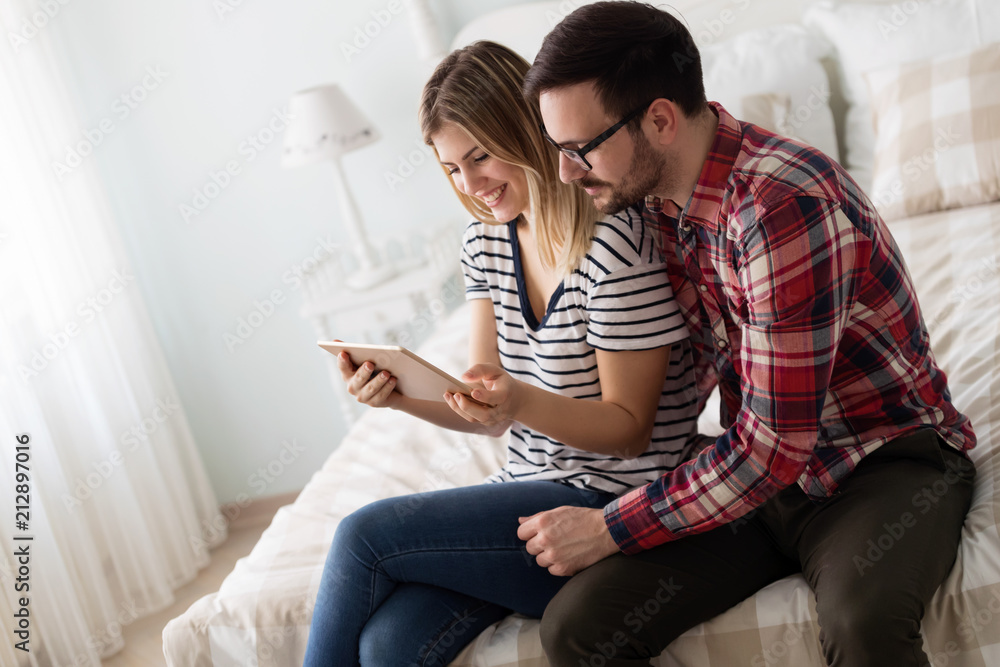 Happy couple using digital tablet in bedroom