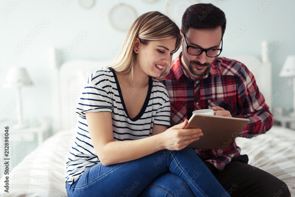 Happy couple using digital tablet in bedroom Happy couple using digital tablet in bedroom