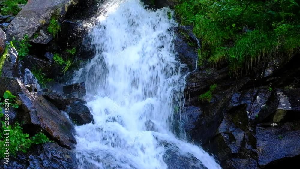 Mountain waterfall in slow motion on a sunny day at summer forest Mountain waterfall in slow motion on a sunny day at summer forest